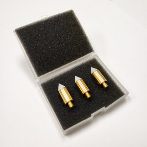 Three white and brass probe tips in a small clear box with the lid open and black foam inserts