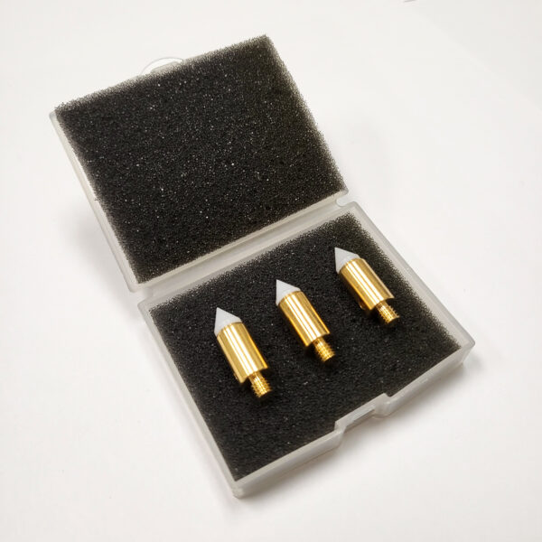 Three white and brass probe tips in a small clear box with the lid open and black foam inserts