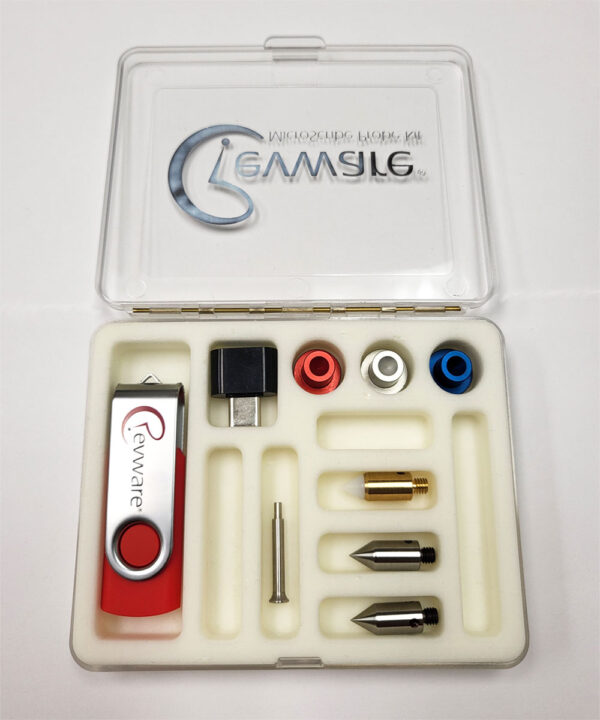 A small clear box on white background with the lid open and a white foam insert showing MicroScribe probe tips and USB drive.