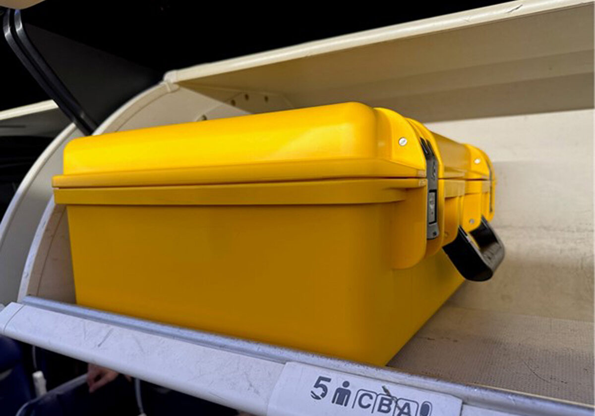 Small Carry Case for MicroScribe in Airplane Overhead A yellow MicroScribe case sitting in an off-white airplane overhead compartment.